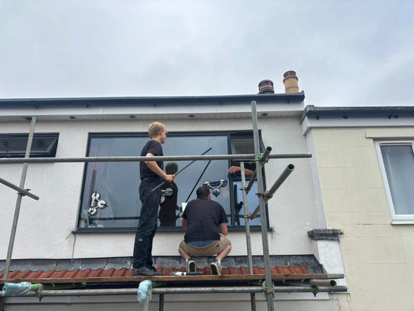 Professional double glazing installers on scaffolding using suction cups to fit new window in Bishopston, Bristol